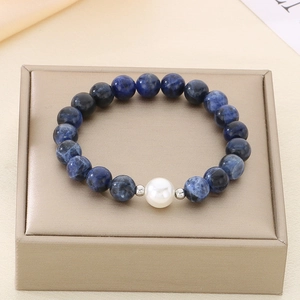 Macro detail of blue sodalite beaded bracelet with white pearl and silver spacers on gold box