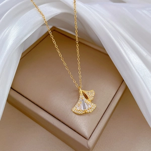 Elegant gold ginkgo leaf necklace with sparkling crystals on silk background