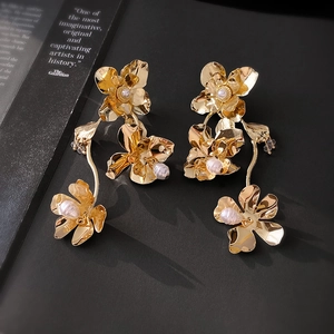 Vue rapprochée de boucles d'oreilles fleur à paillettes dorées et perles baroques