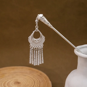 Detailed macro view of silver floral filigree hair pin with elegant hanging tassels