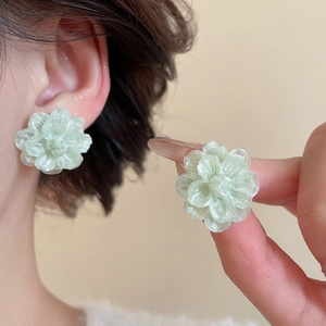 Detailed macro view of translucent green floral earrings with elegant layered petals