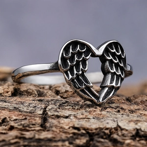 Vintage stainless steel angel wing heart ring with oxidized finish on wood background