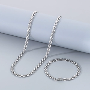 Polished silver geometric square link necklace and bracelet set displayed on a pedestal