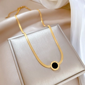 Detail of gold Roman numeral necklace with black round pendant on silk background