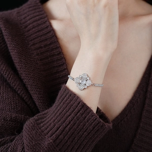 Détail d'un bracelet trèfle en argent avec zircons porté par un mannequin sur un tricot