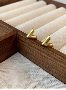 Macro shot of 18K gold V-shaped stud earrings with a 3D geometric minimalist design