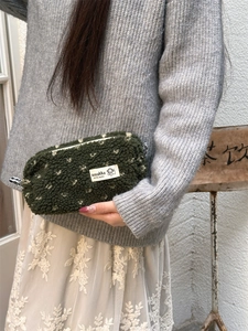 Détail de la trousse en peluche verte à pois blancs avec étiquette de marque tissée