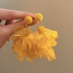 Detailed close-up of yellow raffia and chiffon flower earrings for beach vacation style.