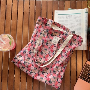 Close-up of vintage floral cotton tote bag with rose patterns on a wooden table