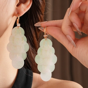 Detail of light green translucent sequin tassel earrings with sparkling zircon accents