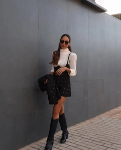 Détail d'une veste noire brodée de fraises et d'une mini-jupe assortie de style doux