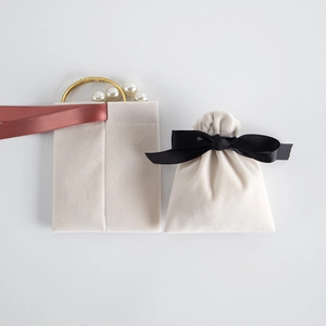 Detail showing cream velvet drawstring jewelry pouches with silk ribbons and pearl bracelet