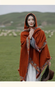 Close-up of orange wool shawl with blue printed border in a scenic grassland landscape