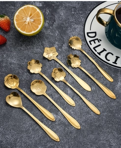 Flat lay of eight golden stainless steel flower-shaped dessert spoons on a dark texture