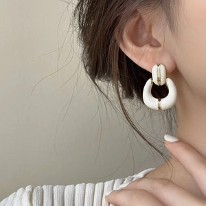 French vintage enamel white C-shaped gold-plated earrings worn by a model in close-up