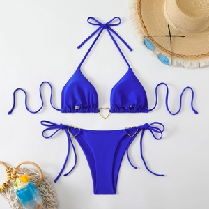 Detail of royal blue bikini with golden heart rings and decorative beach accessories