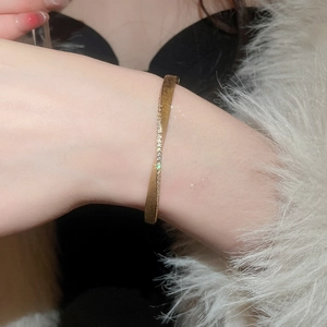 Detail of a gold twisted cuff bracelet with sparkling zircon stones worn by a model