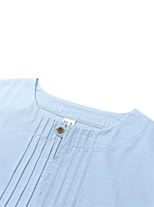 Close-up of pleated cotton linen fabric and button detail on light blue Henley shirt