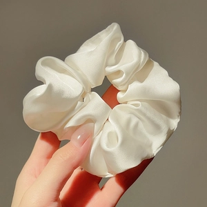 Dettaglio di un grande elastico per capelli in raso bianco perlato effetto seta