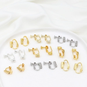 Detail view of various gold and silver screw-on earring converters on white silk fabric