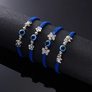 Detailed view of four blue braided evil eye bracelets with silver turtle and elephant charms