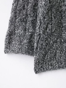 Close-up of gray cable knit sweater texture showing soft wool fibers and ribbed cuffs