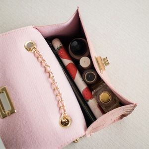 Pink crocodile pattern mini handbag with gold chain strap shown from a 45-degree angle
