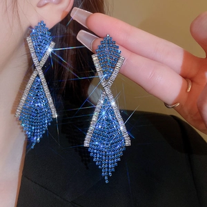 Close-up of sparkling blue rhinestone criss-cross tassel earrings on female model