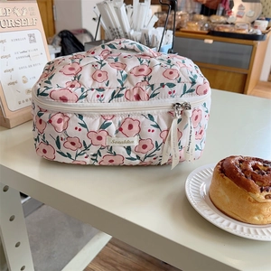 Détail de la trousse de maquillage matelassée avec motif floral rose et tissu doux.
