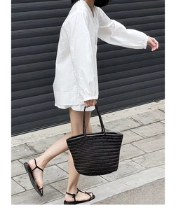 Fashionable street view of a large black woven leather tote bag carried by a model