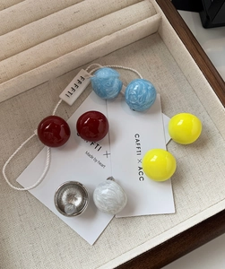 Gros plan de boucles d'oreilles sphériques en résine colorée sur un plateau à bijoux