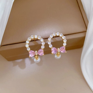 Detailed macro view of bow earrings with pink zircons and white pearls on leather