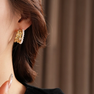 Close-up of vintage lace hollow earrings with pearls and zircons worn by a model