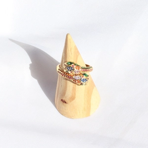 Detailed close-up of rainbow crystal snake ring on wooden stand with golden finish