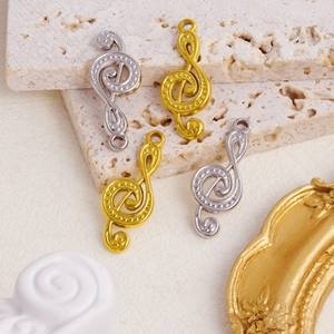 Detailed view of musical note pendants in gold and silver finish on stone background