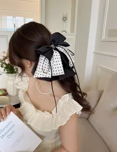 Detail of French chiffon polka dot bow hair claw clip with rhinestones worn by model