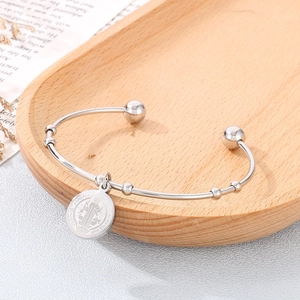 Close-up of silver Saint Benedict Medal charm on a minimalist round bead bangle