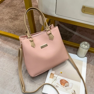 Close-up of pink tote bag with golden handles placed near a candle and magazine