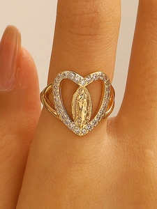 Macro shot of gold heart ring featuring Virgin Mary relief and sparkling pavé stones