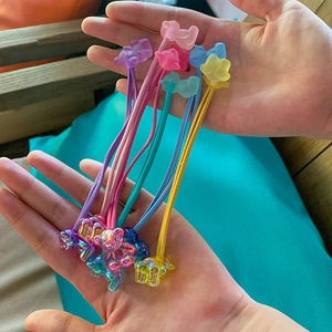 Detail showing iridescent teddy bear hair ties in pastel gummy colors on hands