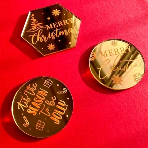 Three-piece gold mirror acrylic Christmas cake toppers on a festive red background