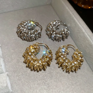 Close-up of gold and silver U-shaped hoop earrings with shimmering pavé crystal setting