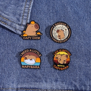 Set of four cute enamel capybara pins with funny quotes on blue denim fabric