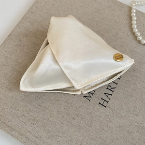Detail of cream satin hair tie featuring a gold engraved Believe In Yourself buckle