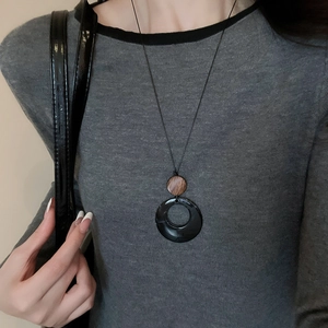 Detail of a vintage long necklace with geometric wood and resin pendants on a gray sweater