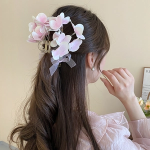Detail view of pink gradient fabric flower hair claw clip with organza bow accessory