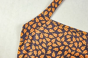 Detailed view of deep purple pleated fabric with orange maple leaf print and clean stitching