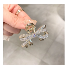 Close-up of a mini gold bow hair claw clip with sparkling rhinestones for hair styling