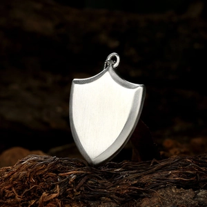 Macro detail of silver shield pendant with brushed texture on vintage dark wood background
