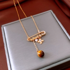 Detail of vintage gold safety pin necklace with tiger eye bead and zircon flower
